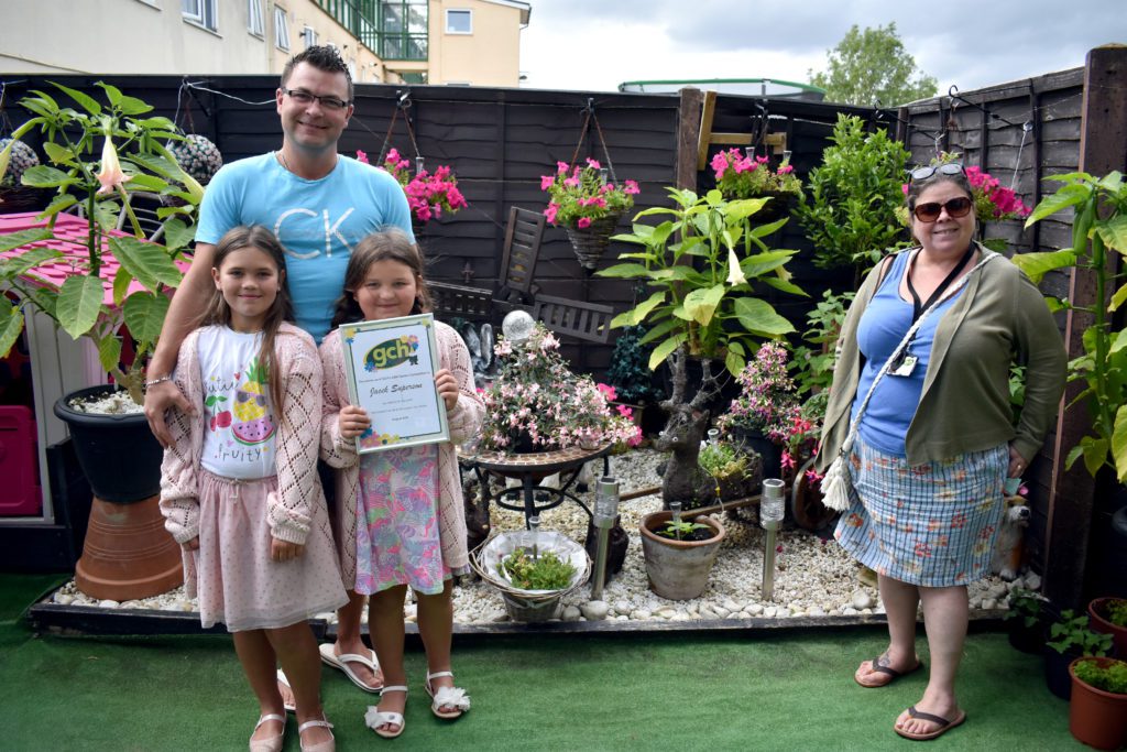 Jacek, his daughters and Housing Officer Amanda stood in garden