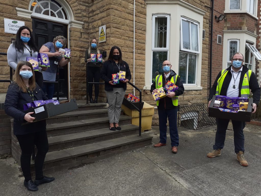 An Image of Novus Staff and the Staff of Caridas House holding the Easter Eggs that have been delivered.