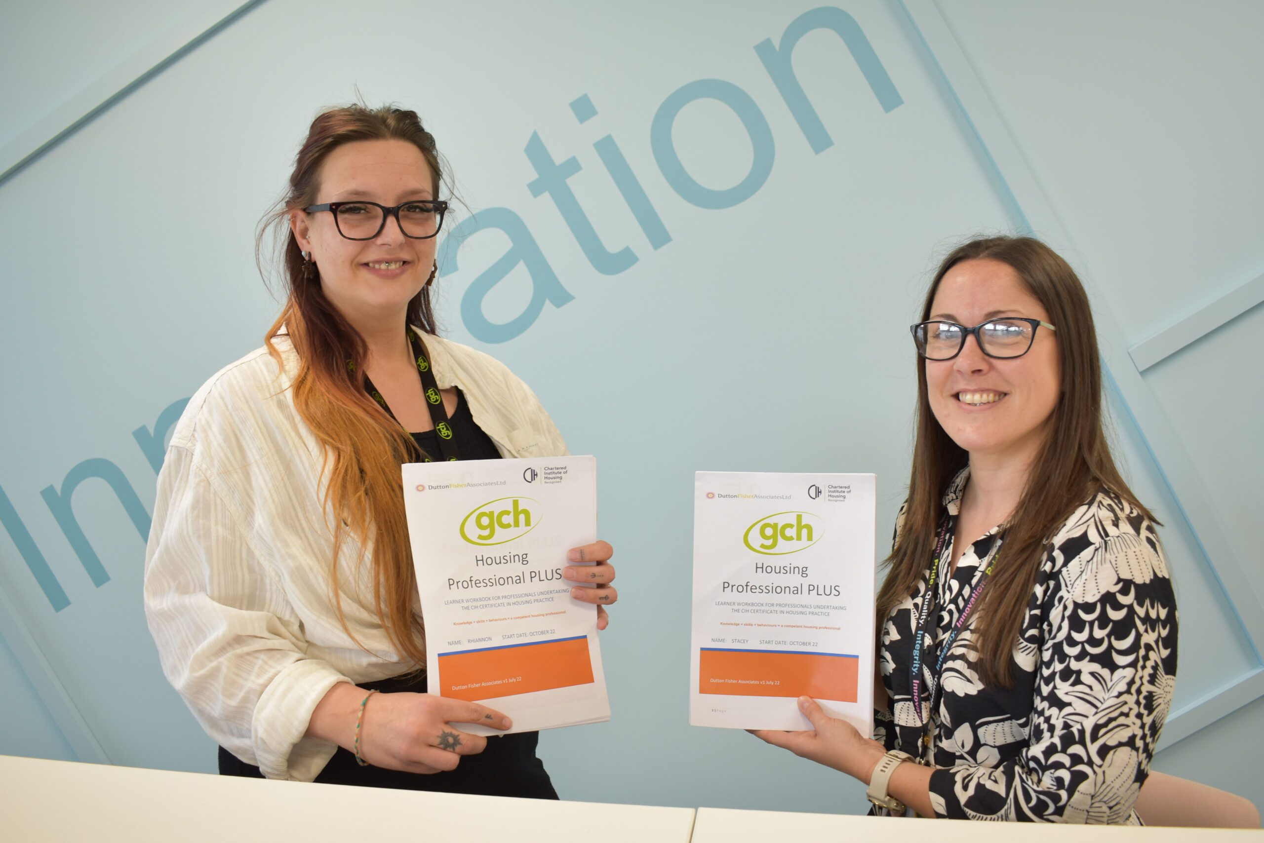 2 smiling ladies holding up workbooks