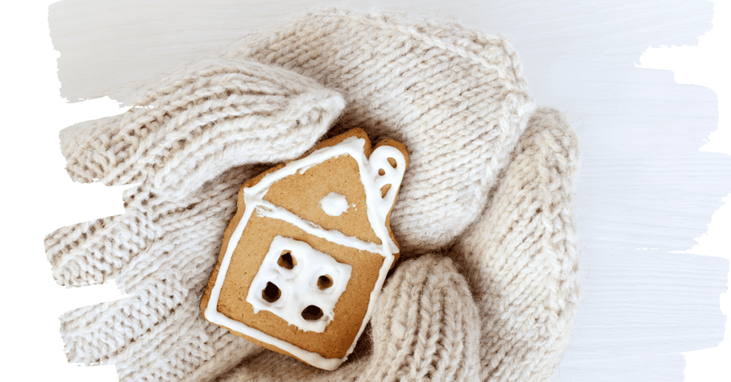 Image shows an iced gingerbread house held in a gloved hand