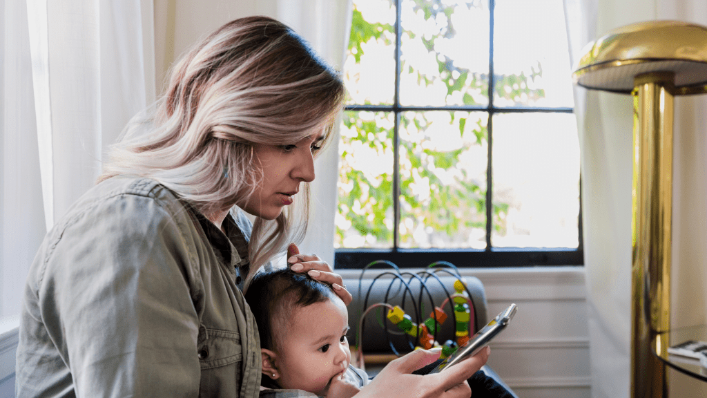 Woman with small child on her knee looking at her phone