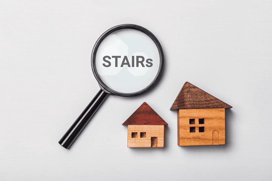 Magnifying glass with the word STAIRS inside, alongside two mini wooden houses.